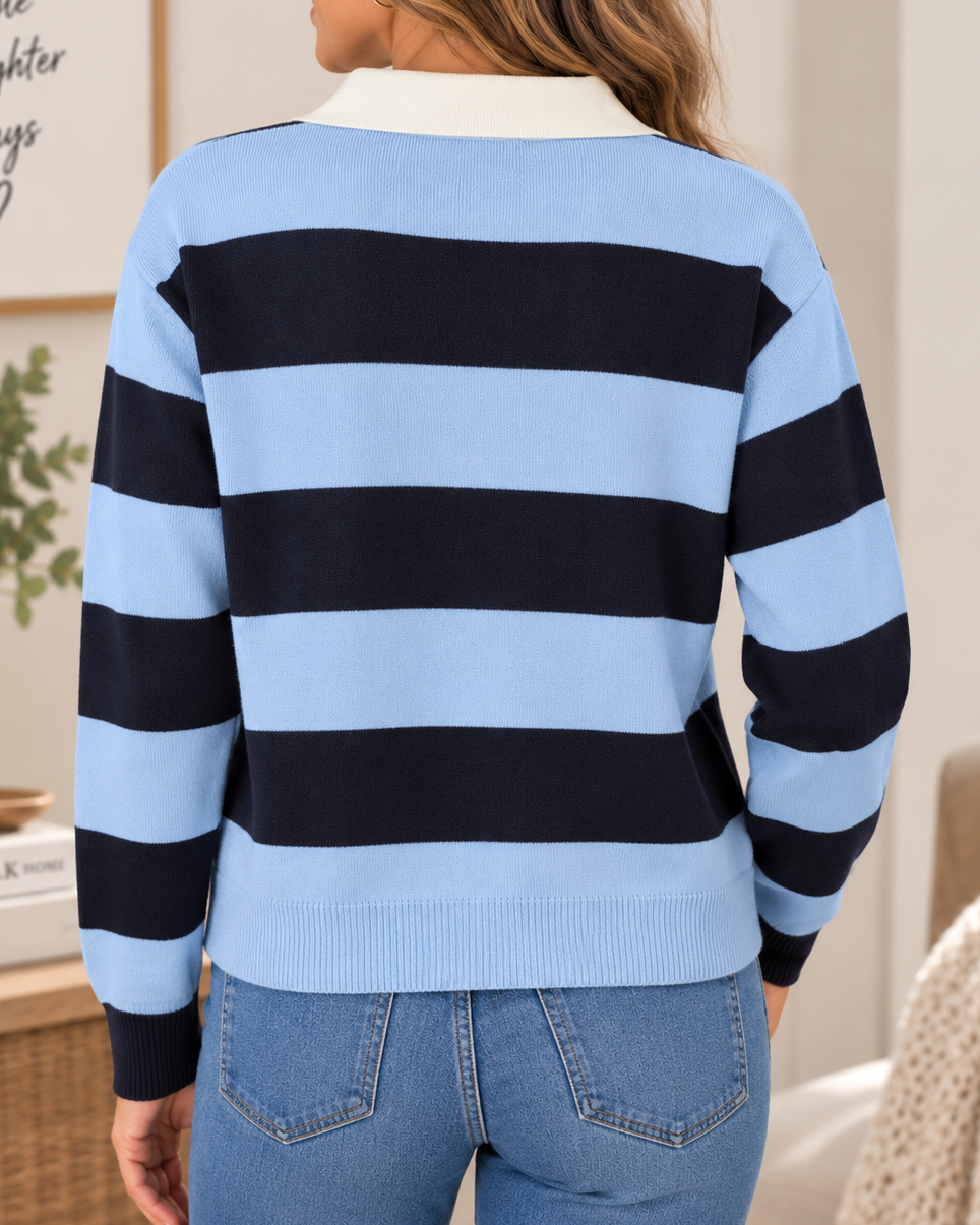 A woman viewed from the back wearing a light blue and navy horizontally striped knit sweater with a white collar, paired with blue jeans in a bright indoor setting.