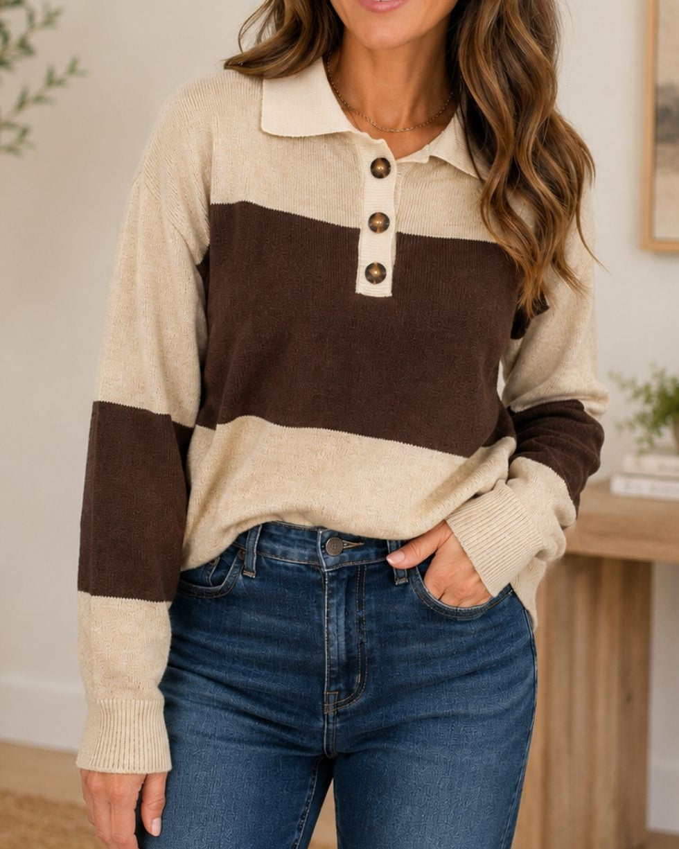A woman wearing a beige and brown color-blocked knit polo sweater with three buttons, paired with blue jeans, in a brightly lit indoor setting.