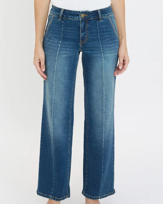 A model wearing a pair of wide-leg blue denim jeans with a faded wash, paired with black pointed-toe heels against a plain white studio background.