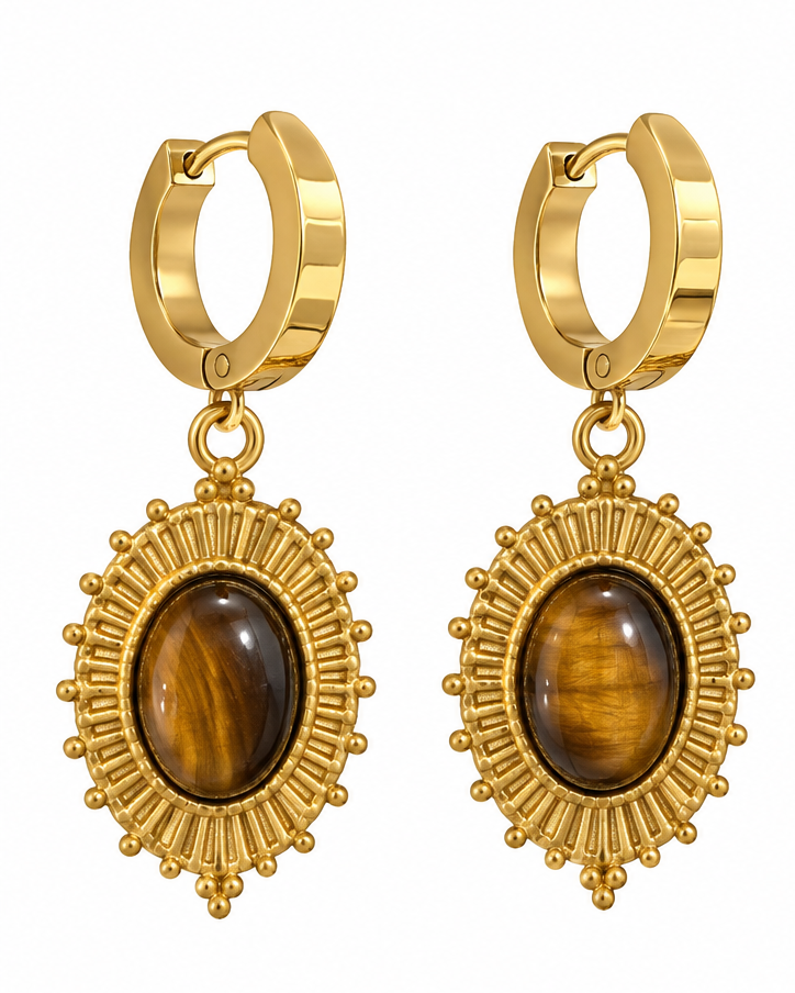 Gold huggie hoop earrings with sunburst detailing and oval tiger's eye stones, shown on a white background and worn on a model's ear.