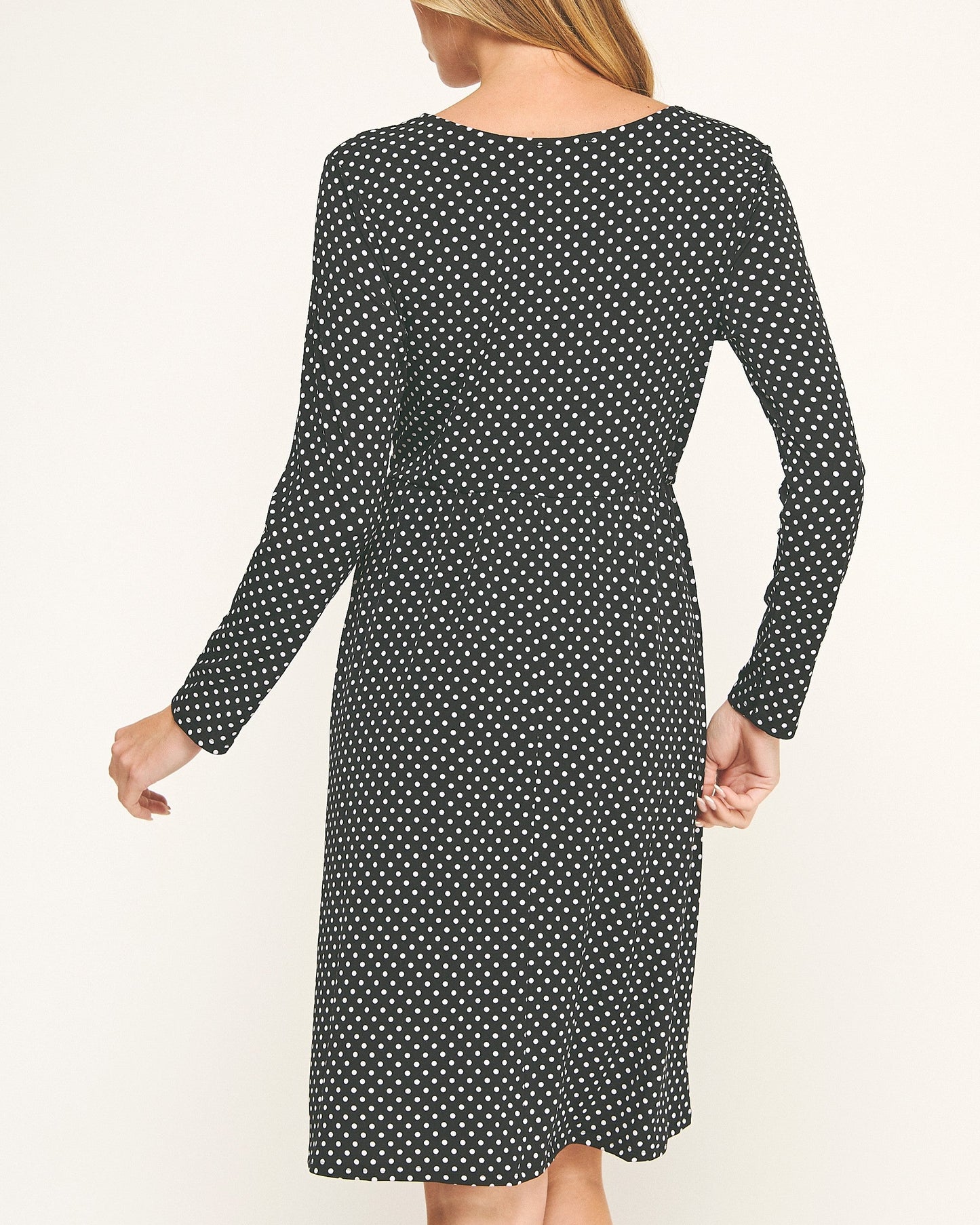 Woman wearing a black polka dot dress on a white background