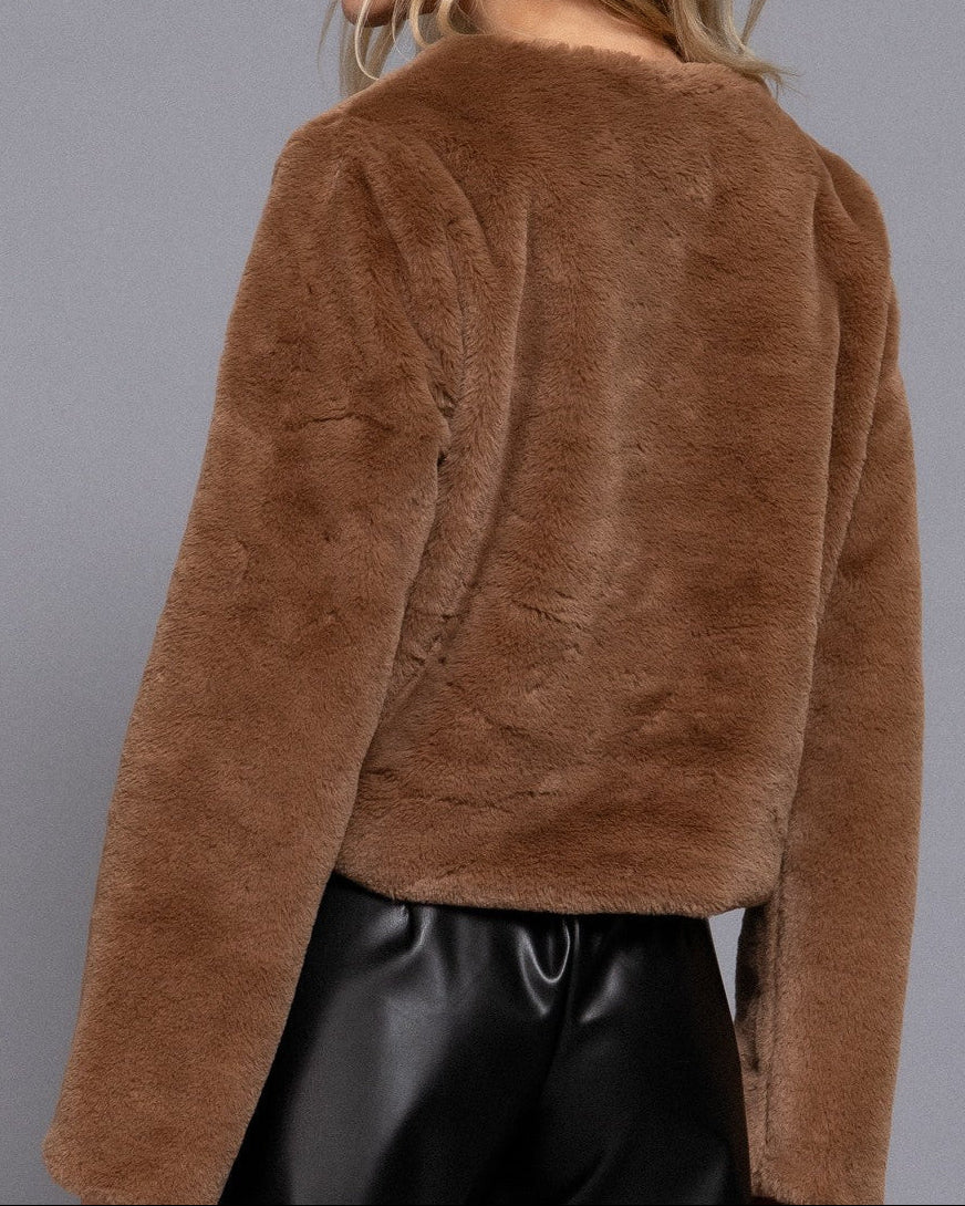Brown fuzzy jacket worn by a person on a gray background