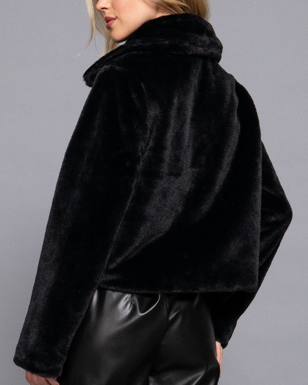 Woman wearing a black fur coat against a gray background