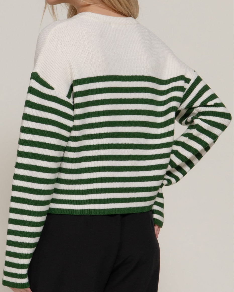 Woman wearing a green and white striped sweater against a plain background