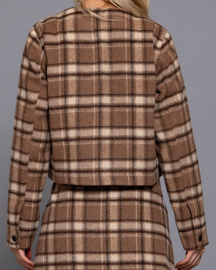 Person wearing a brown plaid dress against a gray background