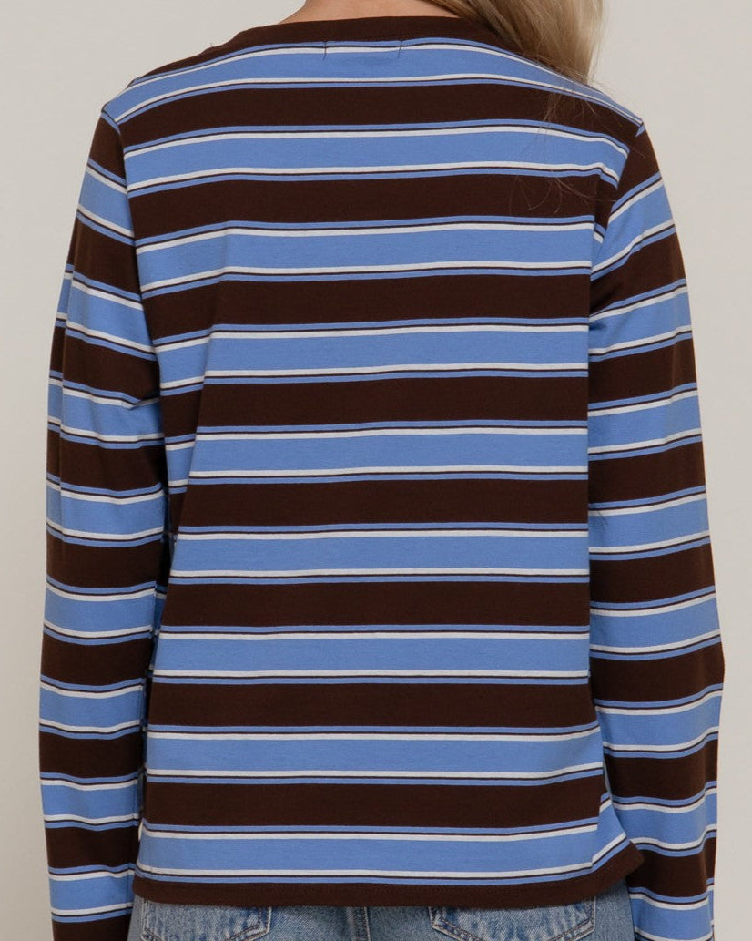 Person wearing a striped long-sleeve shirt with brown and blue horizontal stripes on a plain background