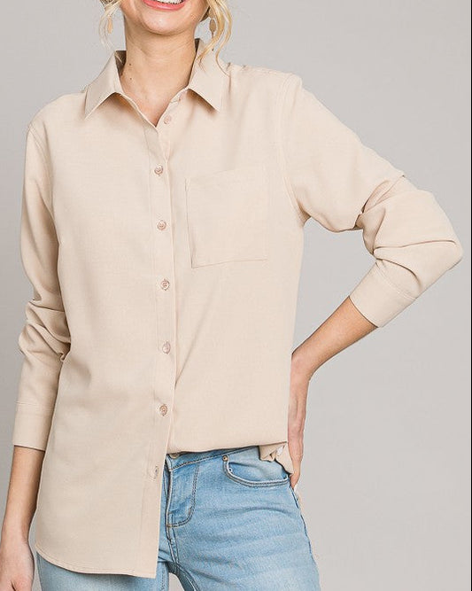 Woman wearing a beige button-up shirt and blue jeans against a gray background