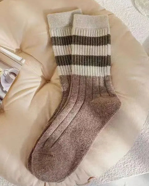 Striped socks on a pillow with a book and glass of water in the background