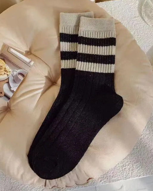 Black and white striped socks on a beige cushion with a soft background