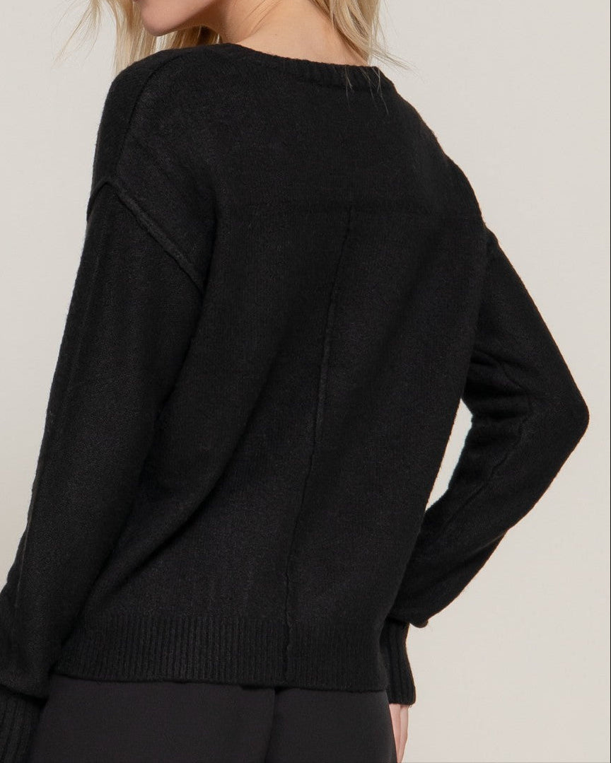 Woman wearing a black sweater against a plain background