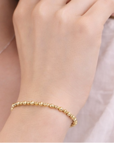 Gold bracelet on a wrist with a blurred background