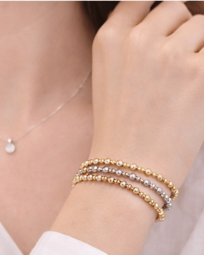 Close-up of a person wearing three beaded bracelets on their wrist.