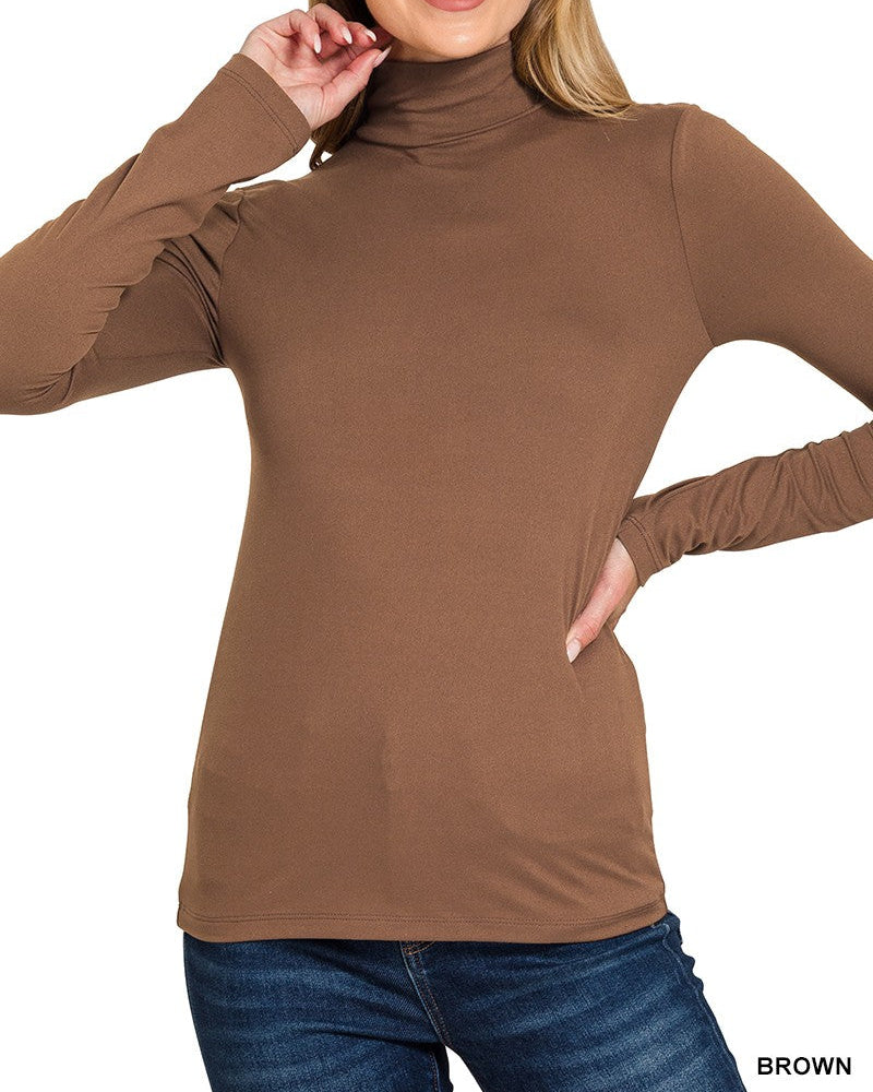Woman wearing a brown turtleneck sweater with blue jeans on a white background