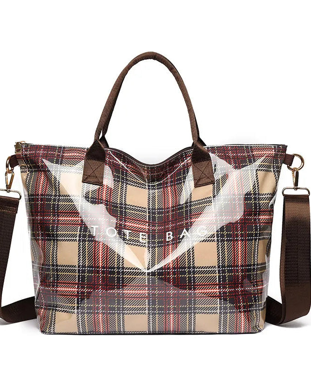 A tote bag with a beige, red, and black plaid pattern, featuring a clear front panel, brown leather handles, and a brown shoulder strap.