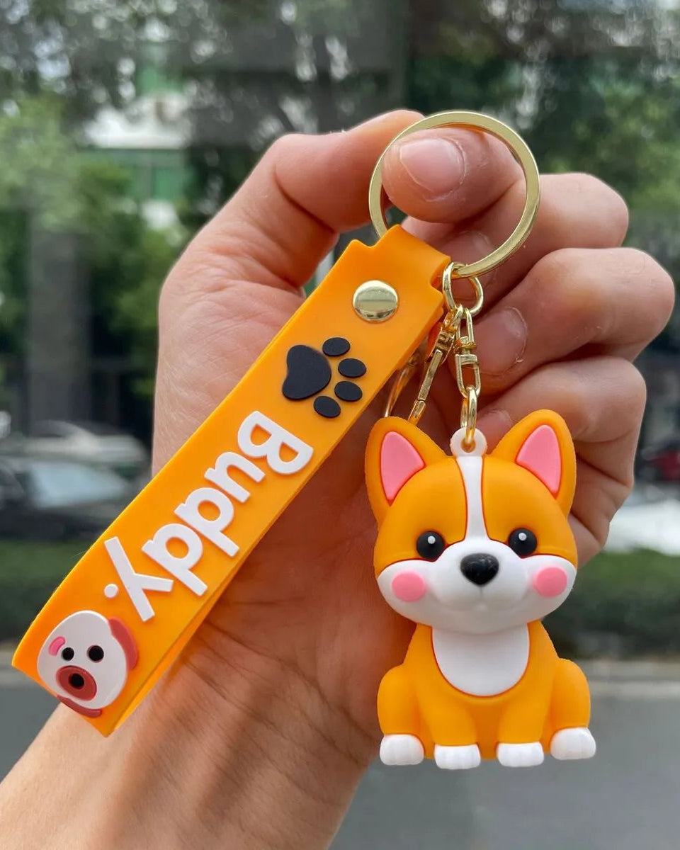 Hand holding a keychain with a cartoon dog design and an orange tag labeled 'Buddy'.
