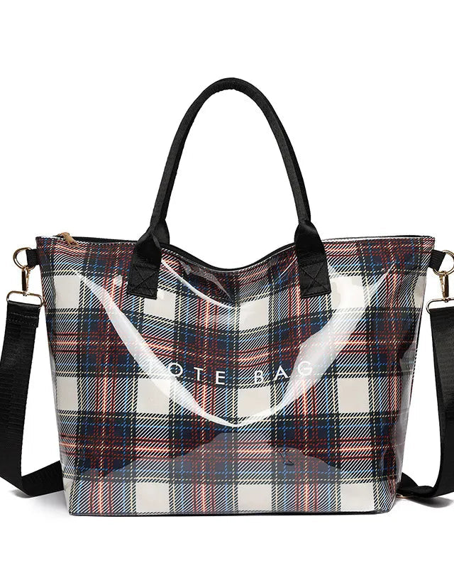 A clear plastic tote bag with a black handle and a black shoulder strap, featuring a red, blue, and white plaid pattern on the sides. The bag has a transparent front pocket with the words 'NOTE BAG' printed in white, and gold-tone hardware.
