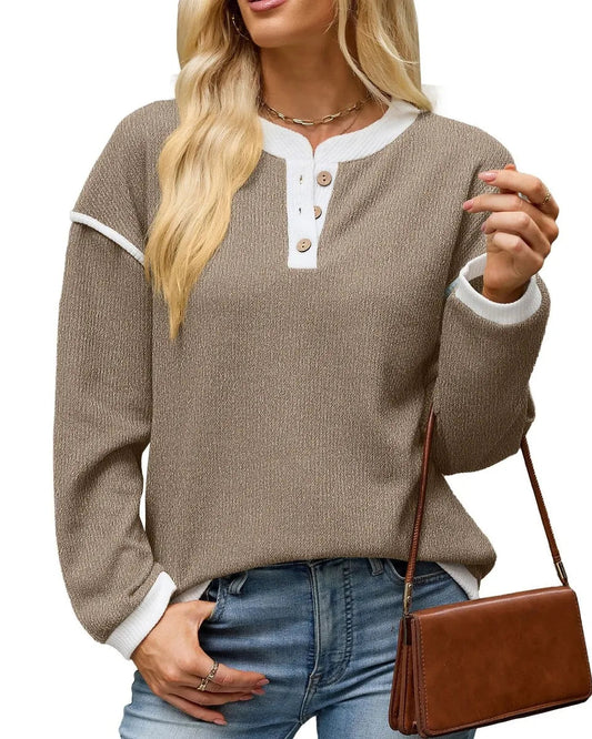 A woman wearing a taupe-brown long-sleeve henley sweater with white ribbed trim and buttons, paired with blue jeans and holding a brown crossbody bag, against a plain white background.