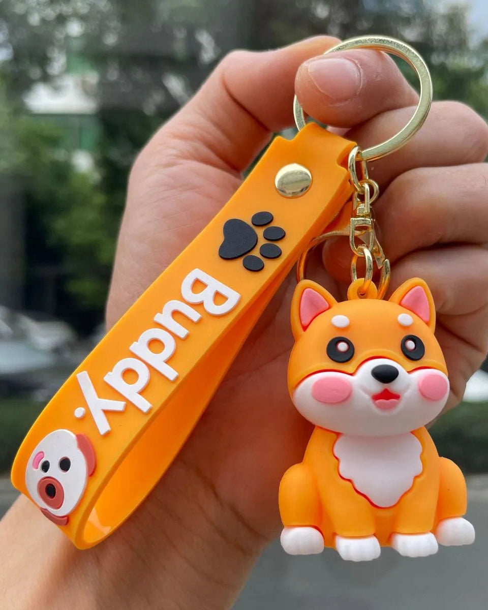 Hand holding an orange 'Buddy' keychain with a dog figure.