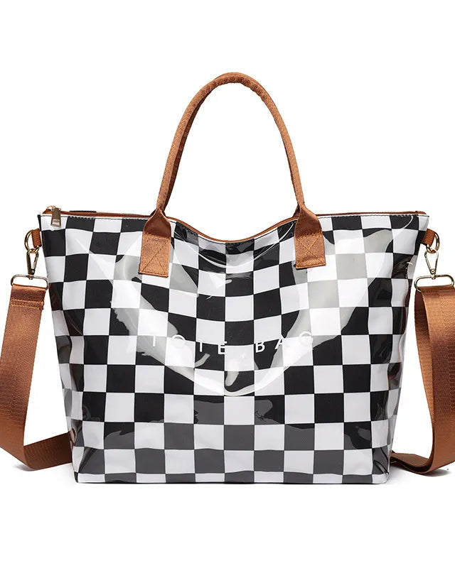 A glossy black and white checkered tote bag with brown leather-look handles and a matching brown shoulder strap, shown on a plain white background.