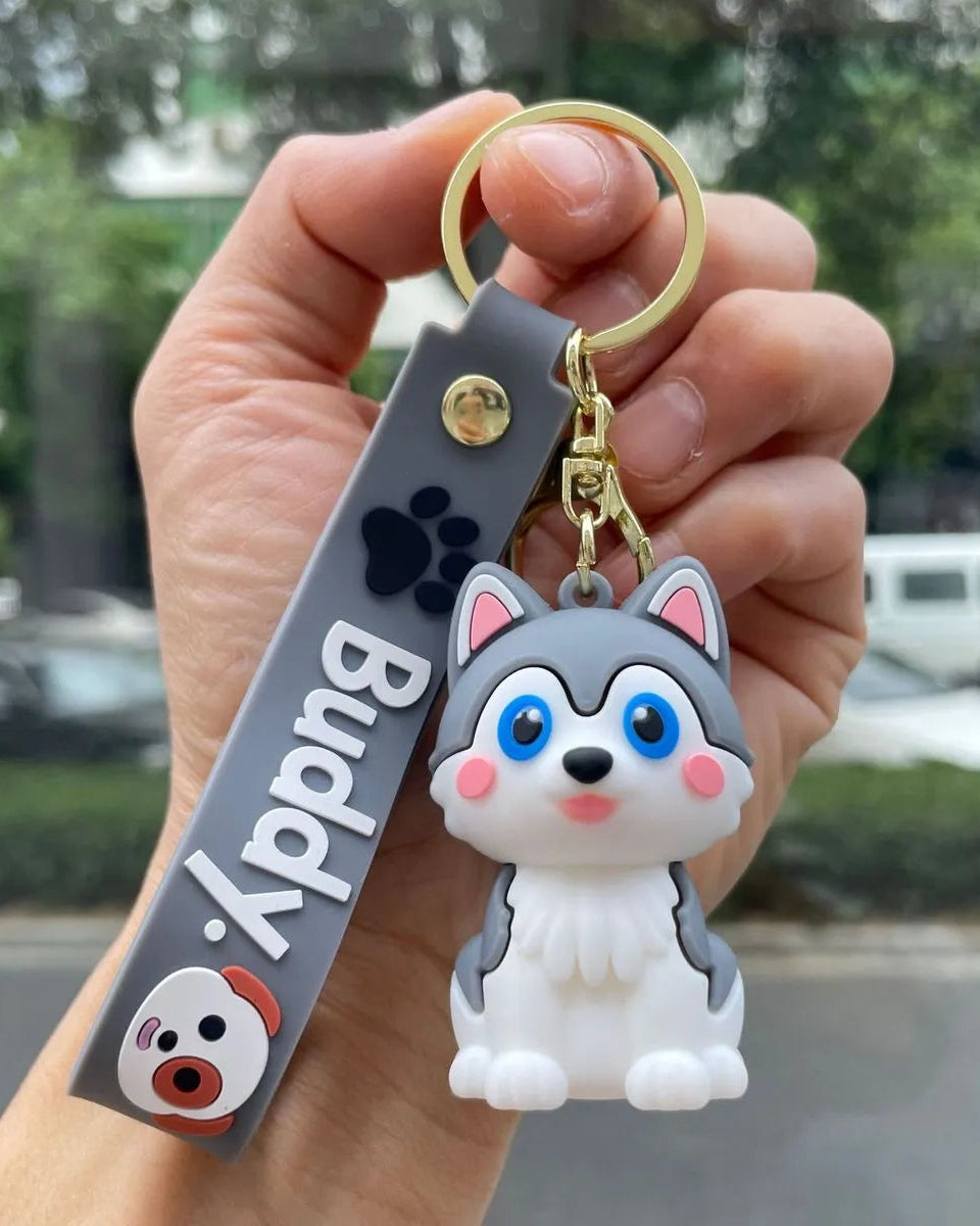 Hand holding a keychain with a dog design and 'Buddy' tag.