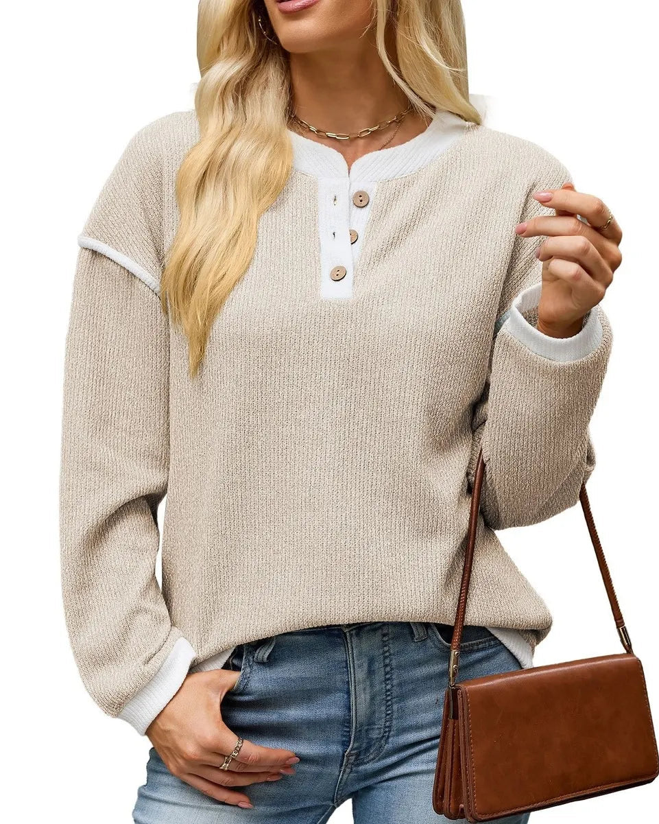A woman wearing a beige ribbed knit Henley sweater with white trim and button details, paired with blue jeans and carrying a brown crossbody bag, set against a plain white background.