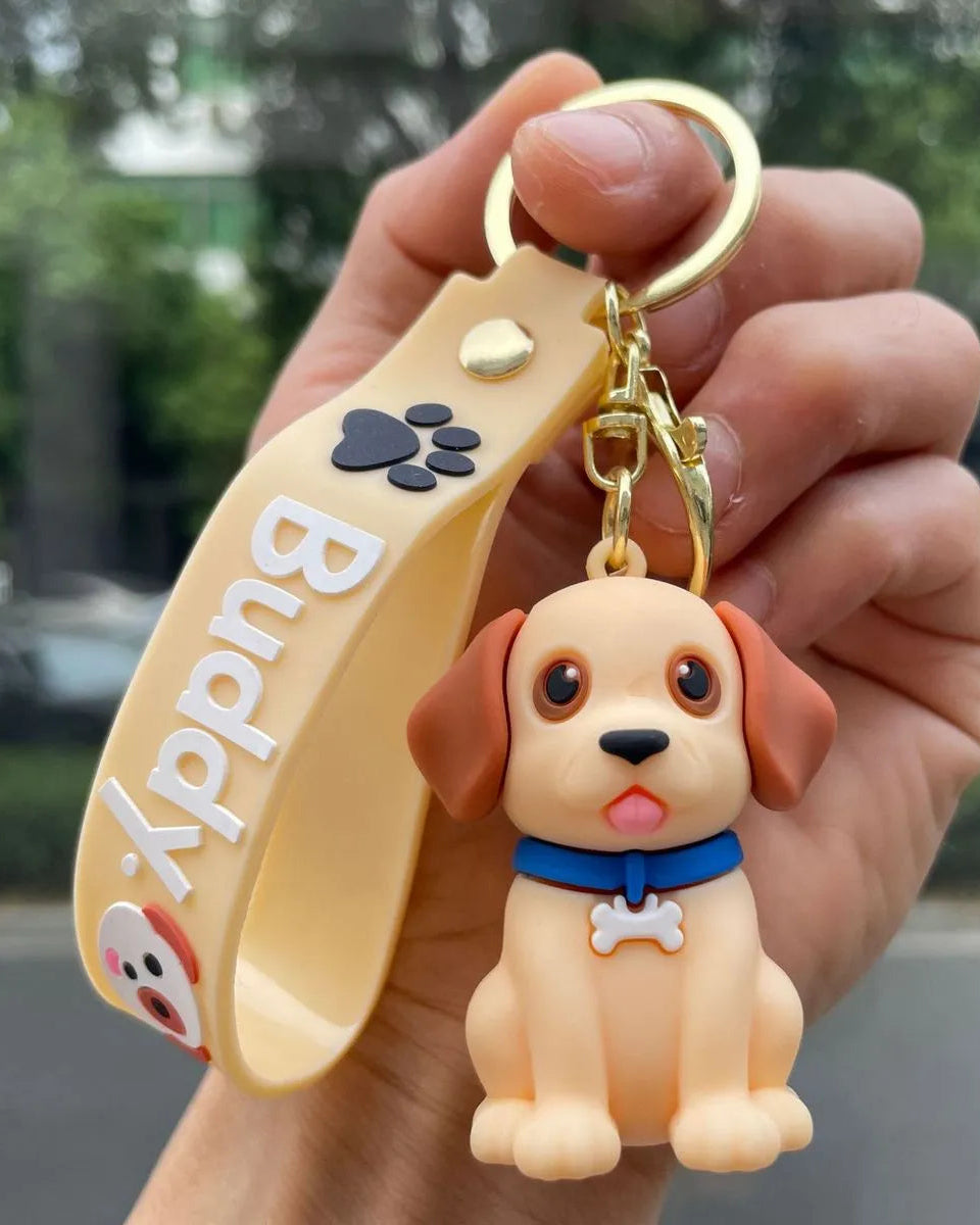Keychain with a dog figure and 'Buddly' branding held in a hand outdoors.