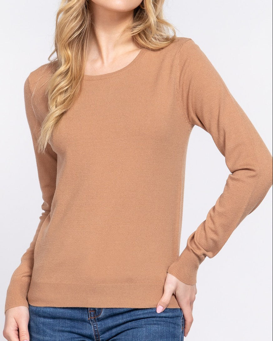 Woman wearing a brown sweater and blue jeans against a white background