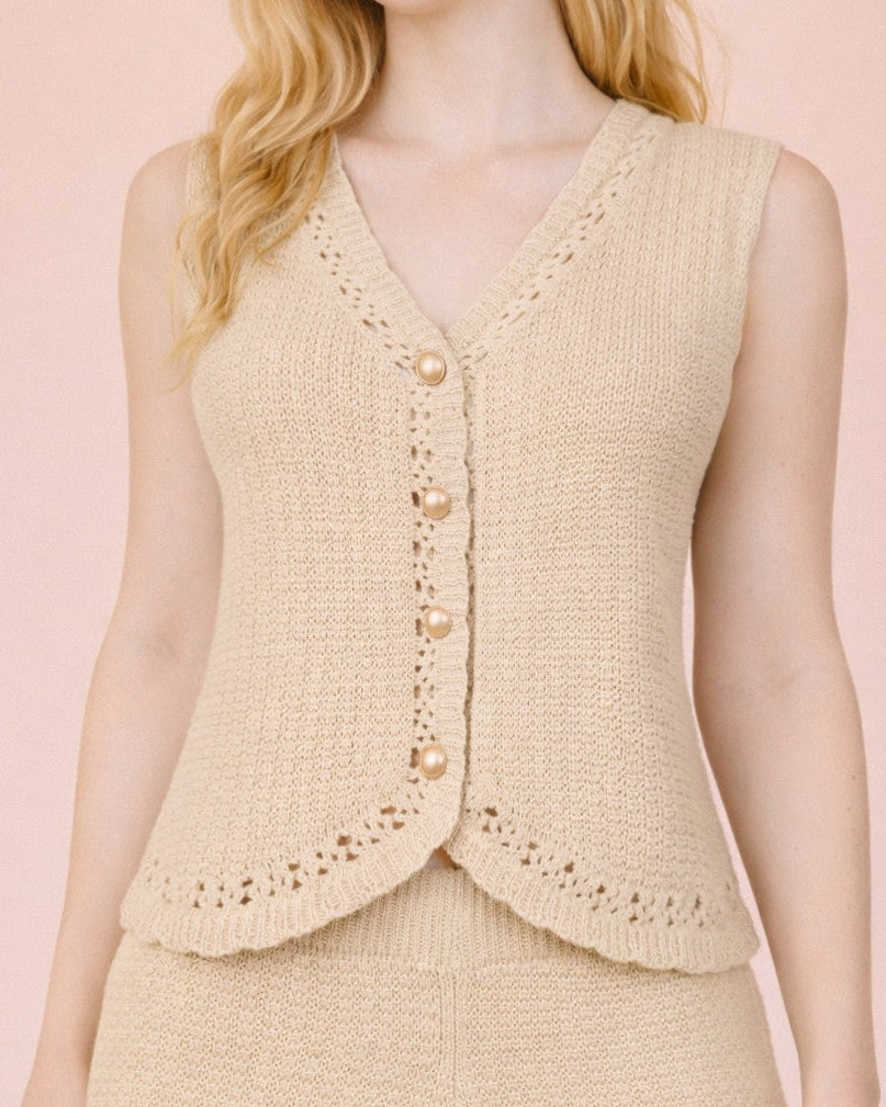 Woman wearing a beige knitted vest over a matching skirt on a pink background