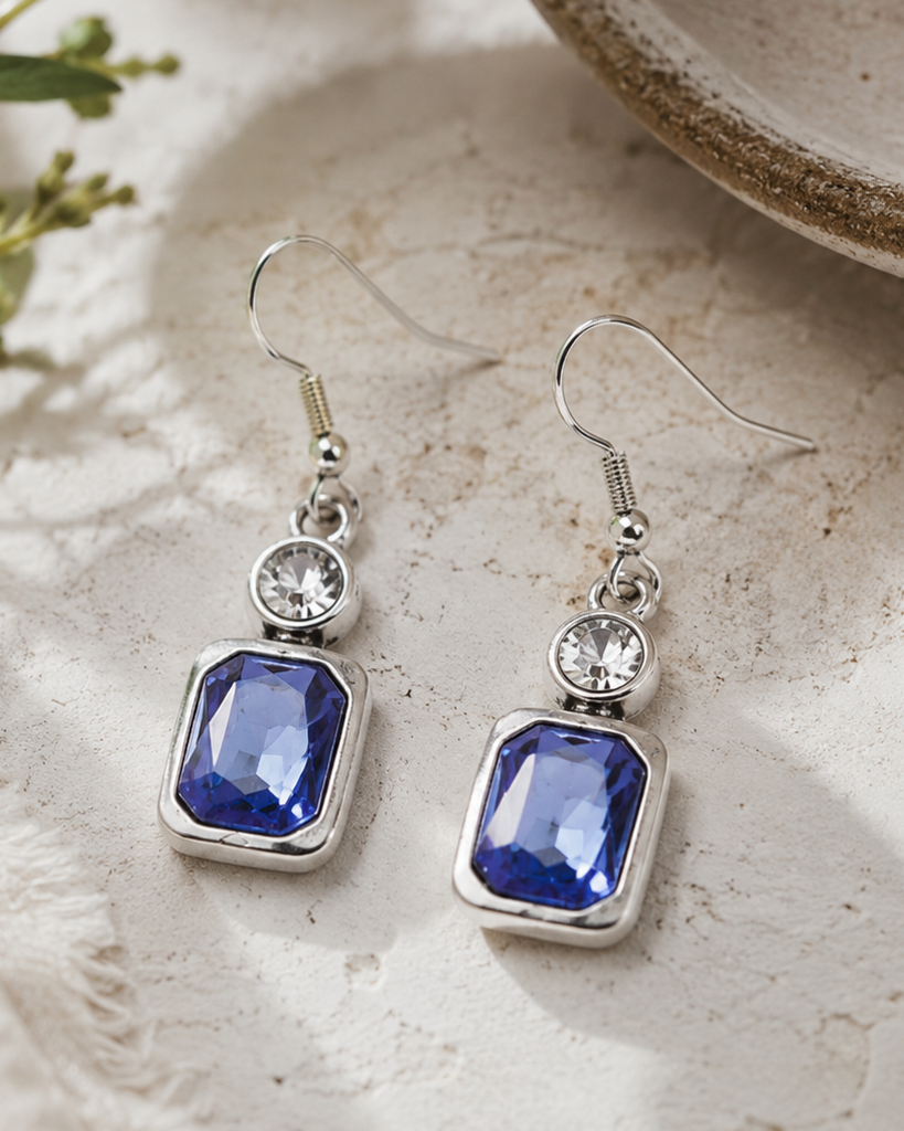 Pair of blue gemstone earrings with silver hooks on a textured surface.