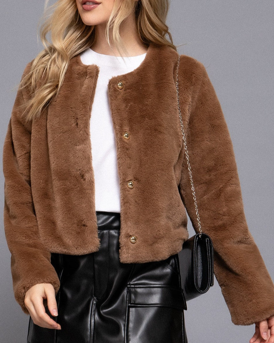 Person wearing a brown fuzzy jacket with a plain background