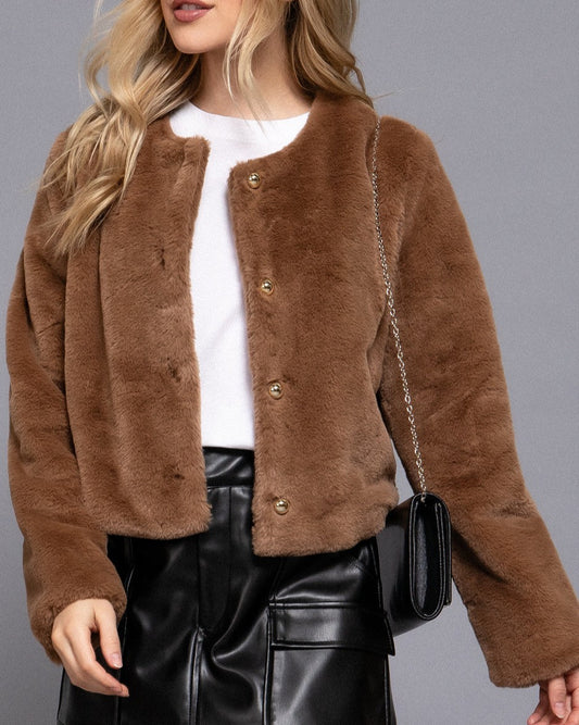 Person wearing a brown fuzzy jacket with a plain background