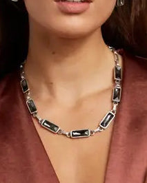 Woman wearing a deep neckline top with jewelry on a plain background