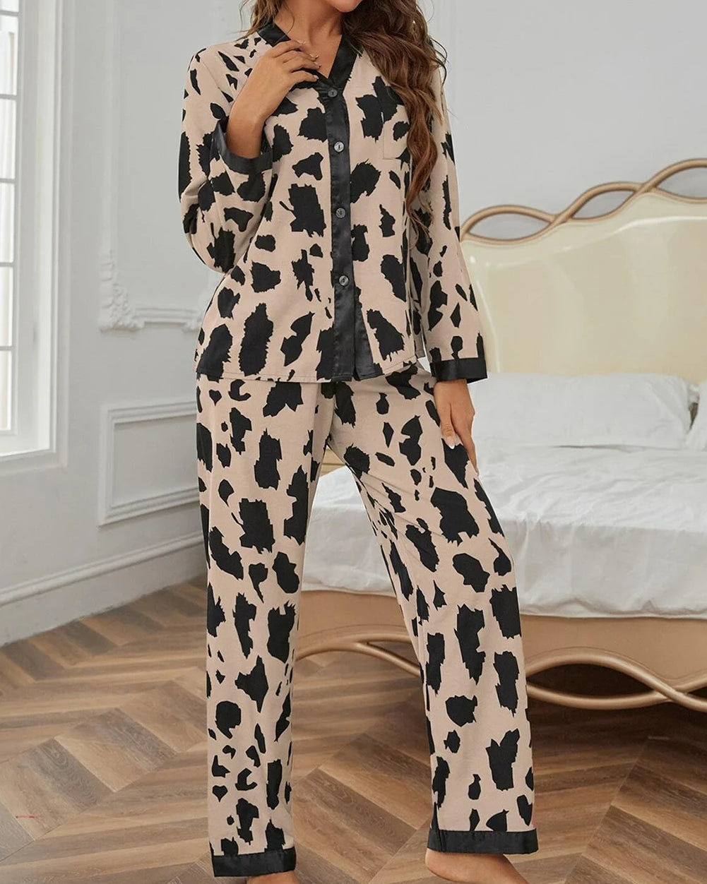 Woman wearing a cow print pajama set in a bedroom.