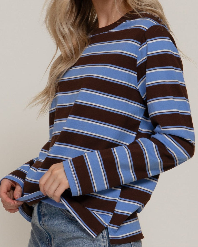 Woman wearing a brown and blue striped sweater against a plain background