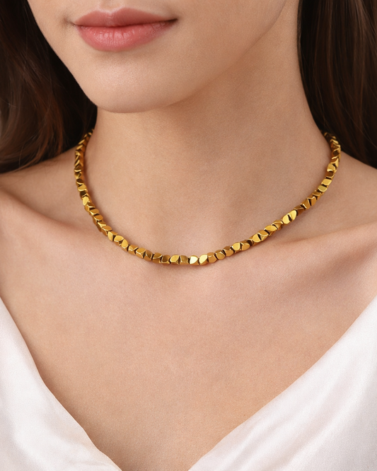 Gold necklace worn by a person with a white top