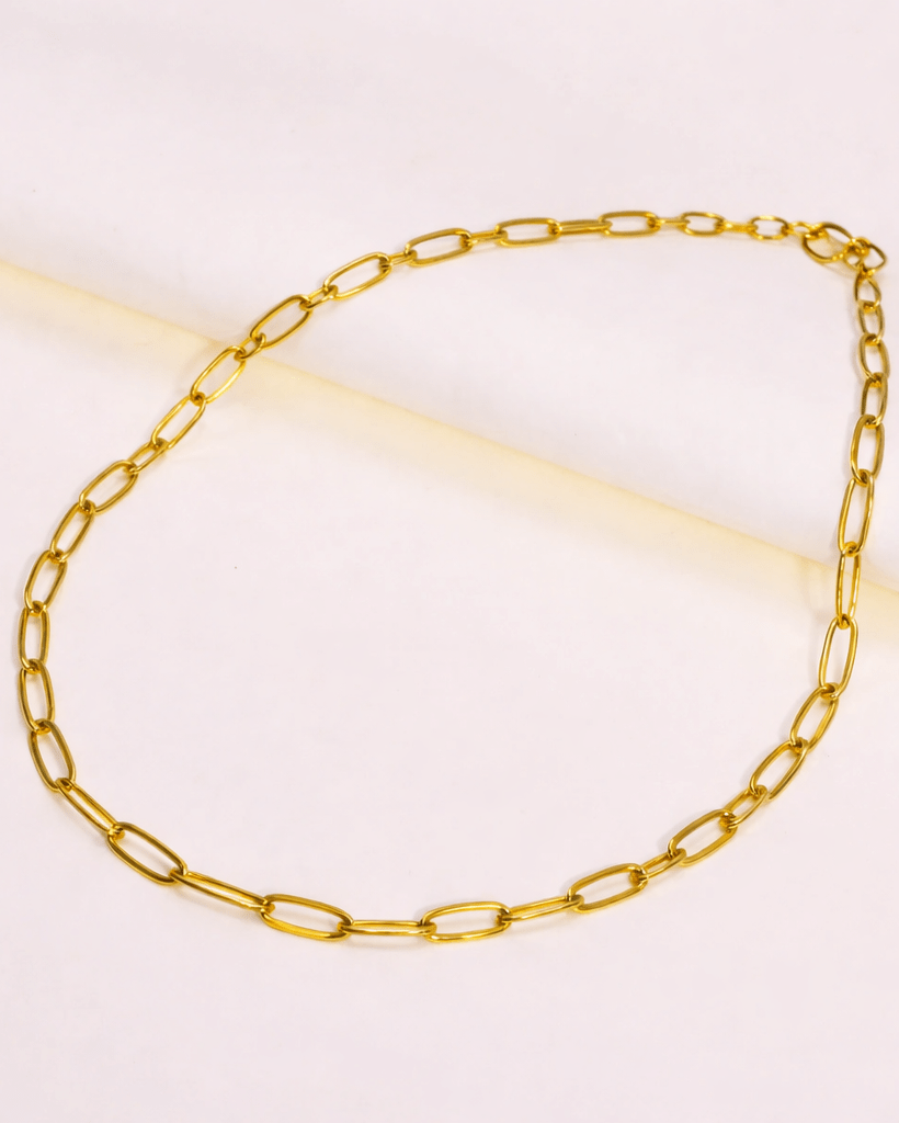 Gold chain necklace on a light pink background