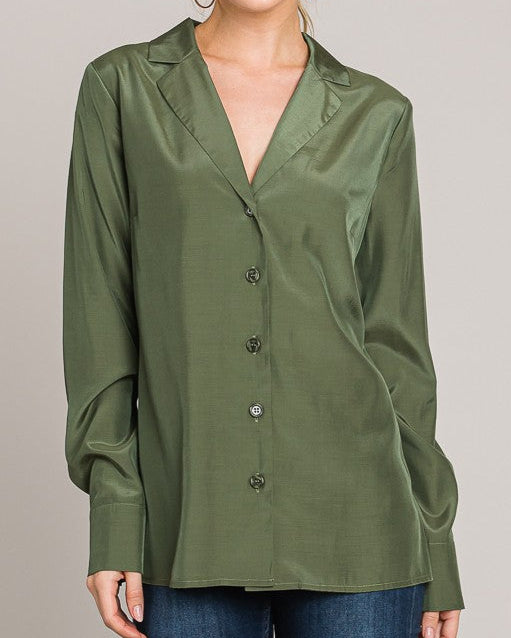 Woman wearing an olive green blouse with a plain background