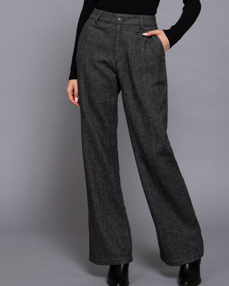 Woman wearing a black turtleneck and gray wide-leg pants on a gray background