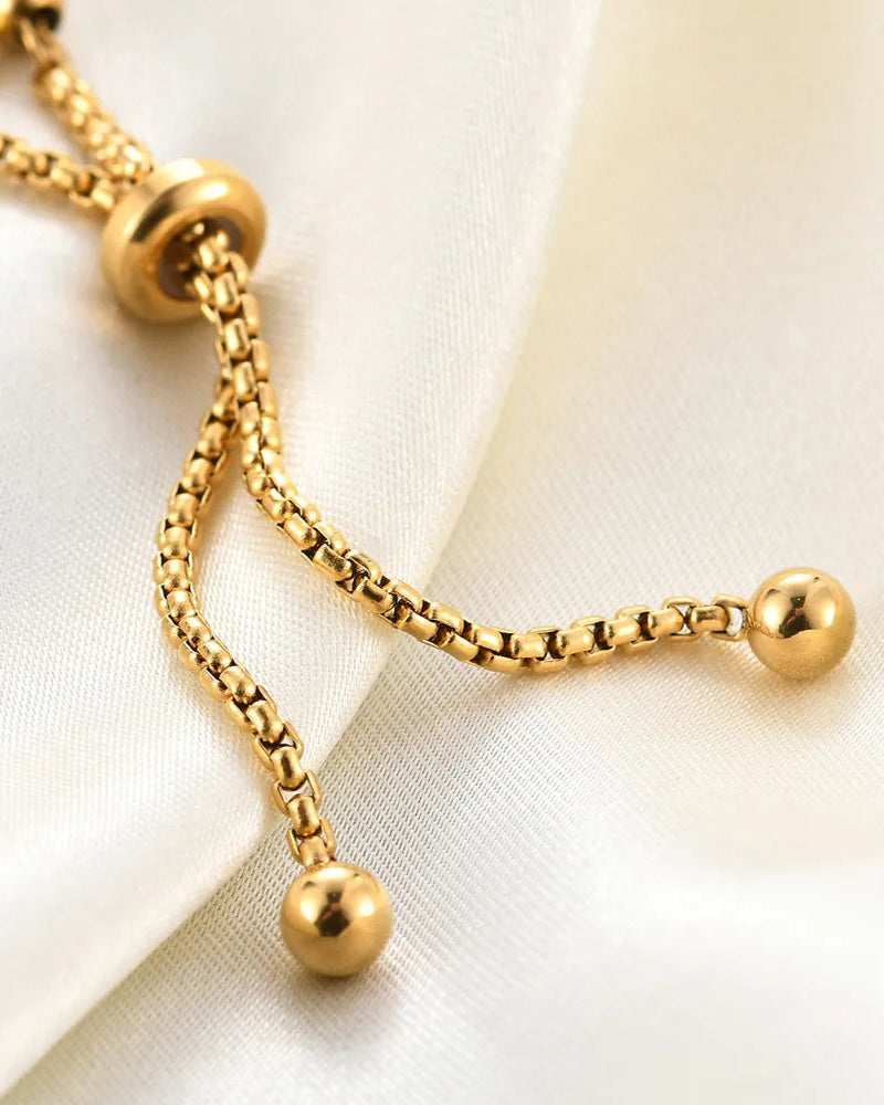 Gold bracelet with spherical beads on a white fabric background