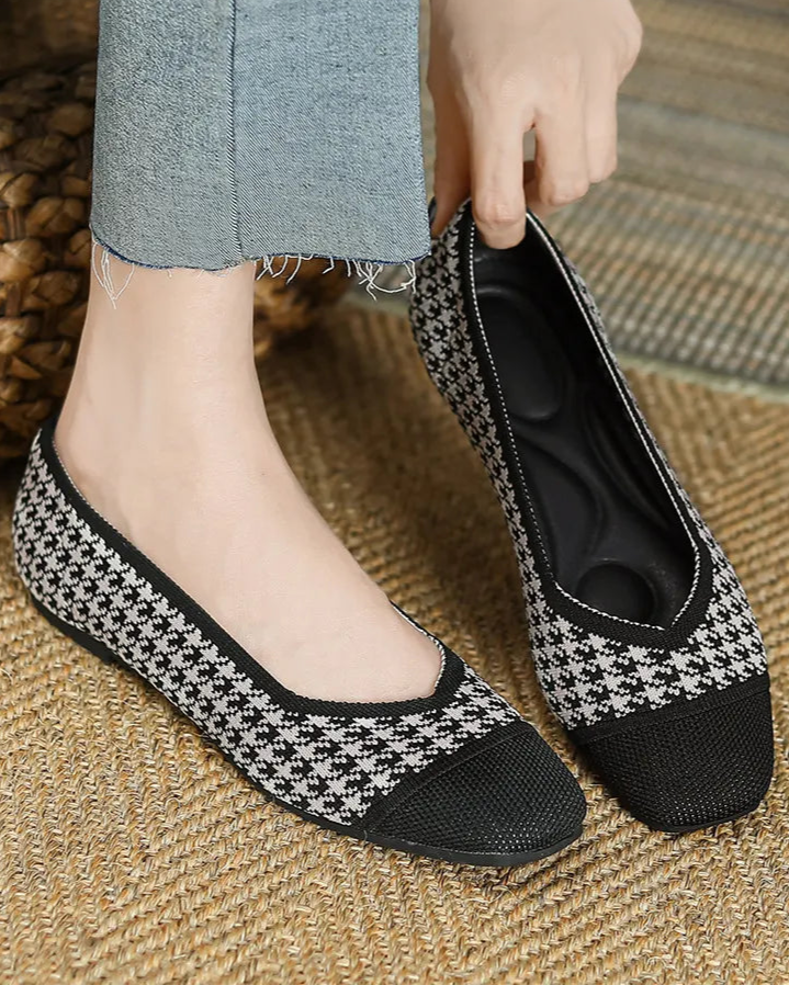 Person wearing black and white checkered shoes on a textured floor.