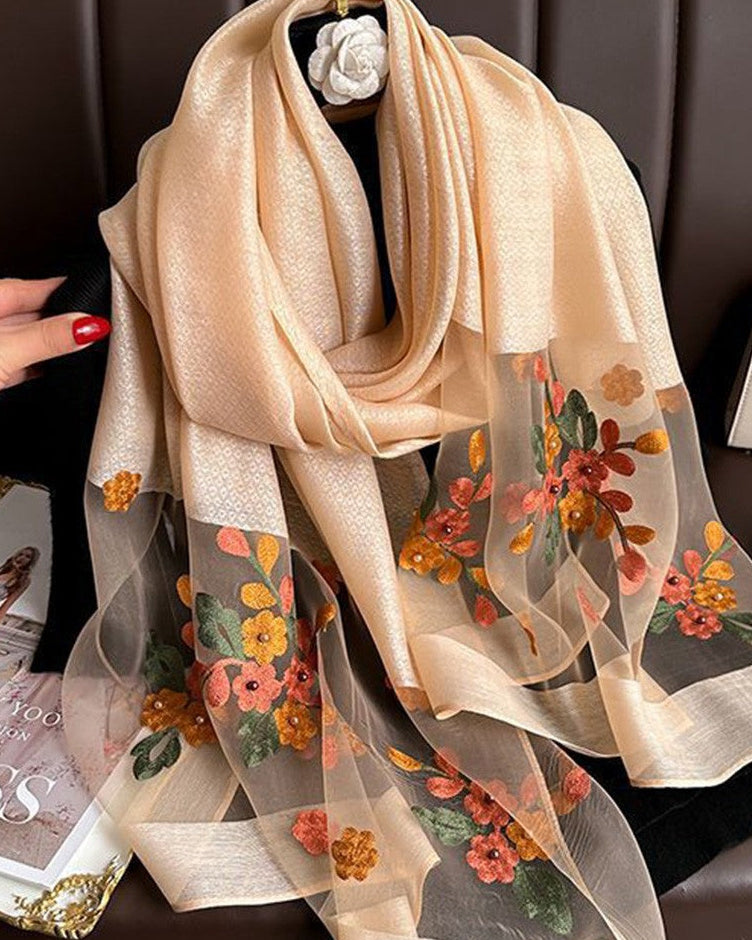 Beige scarf with floral patterns on a mannequin against a dark background