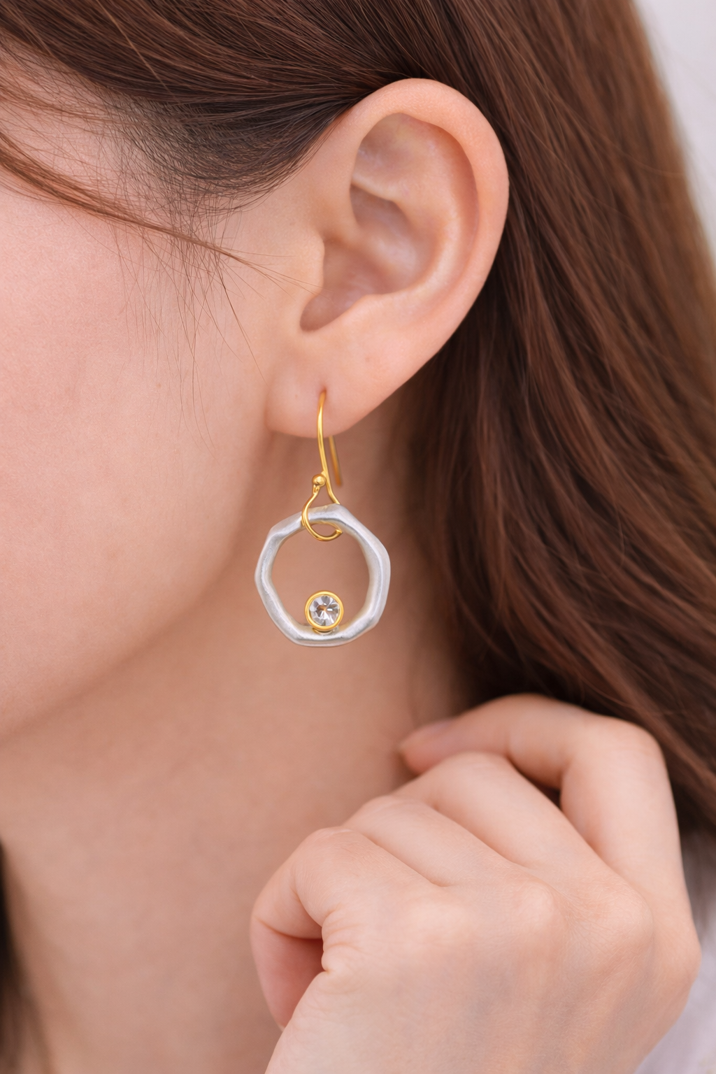 Close-up of a person wearing a gold and silver earring.