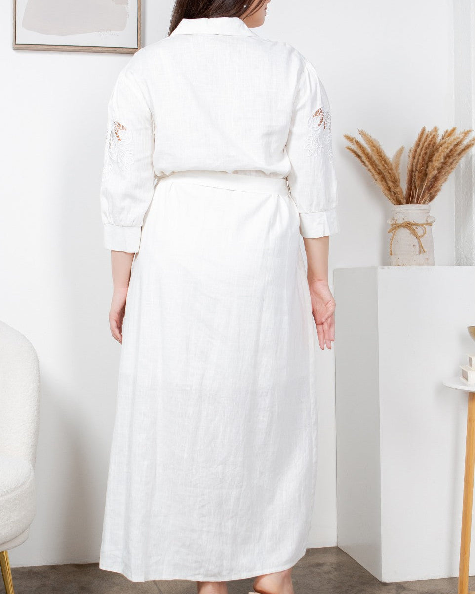 Woman wearing a long white dress in a minimalistic room.