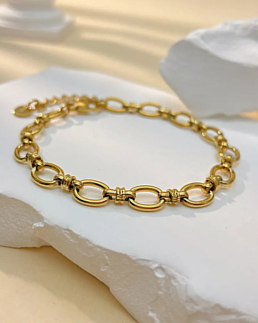 Gold chain bracelet on a white stone surface