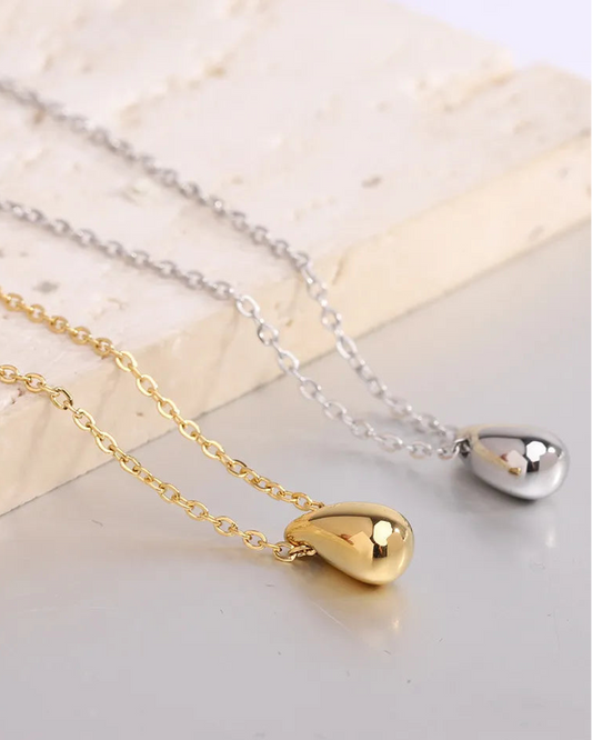 Gold and silver stainless steel necklaces displayed on beige stone