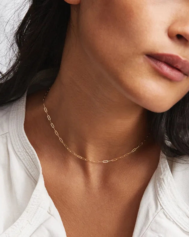 Close-up of a woman wearing a gold necklace with a blurred background