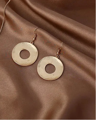 Gold necklace and earrings on a brown fabric background