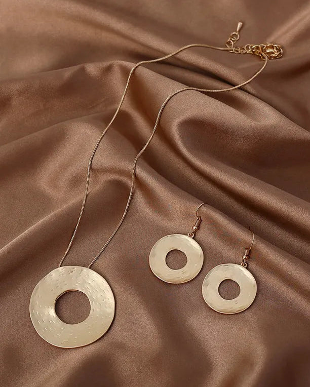 Gold necklace and earrings on a brown fabric background