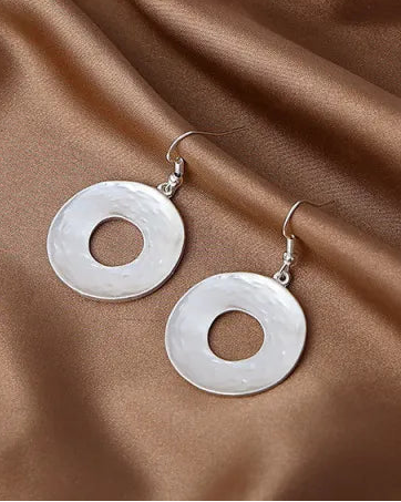 Silver necklace and earrings on a brown fabric background