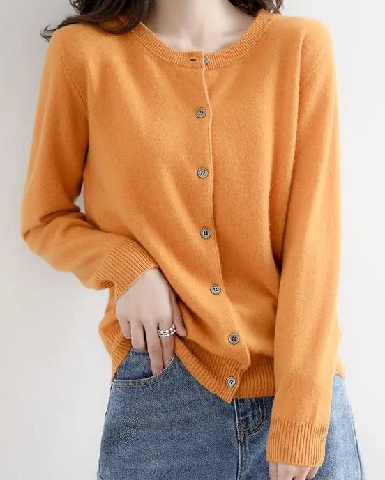 Person wearing a mustard cardigan and blue jeans against a plain background